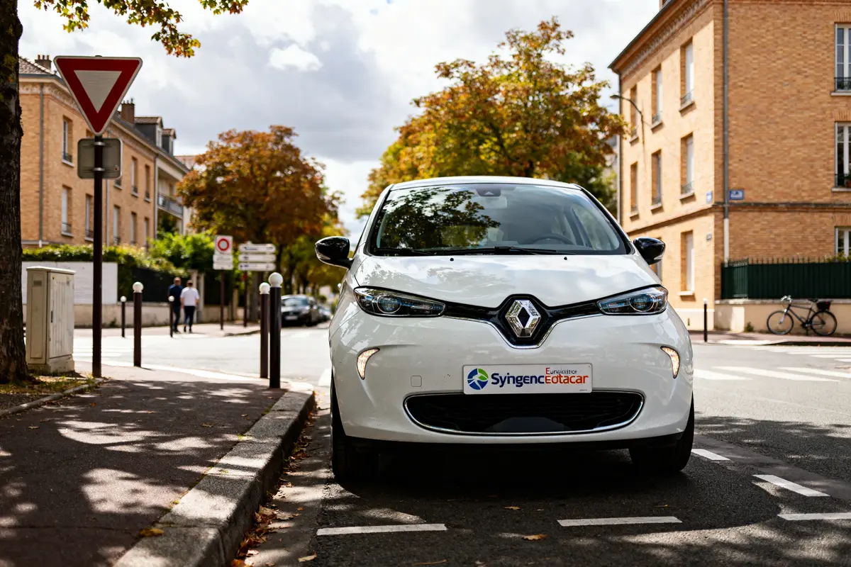 Voiture Renault blanche en ville avec logo synergie Eurodatacar sur la plaque avant