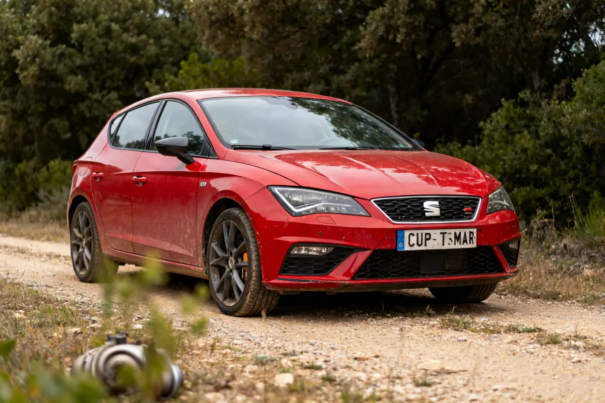 Voiture rouge Cupra Terramar sur chemin de terre entouré de végétation