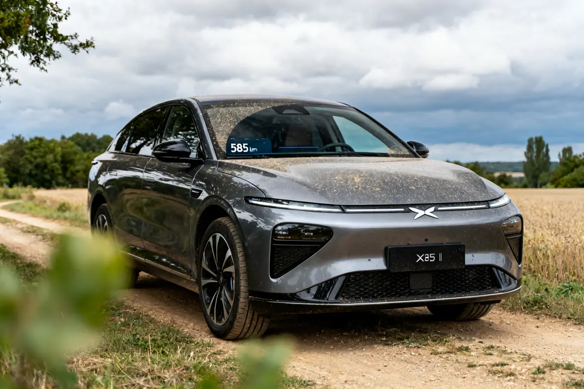SUV électrique Xpeng G9 gris sur chemin rural avec autonomie affichée de 585 km