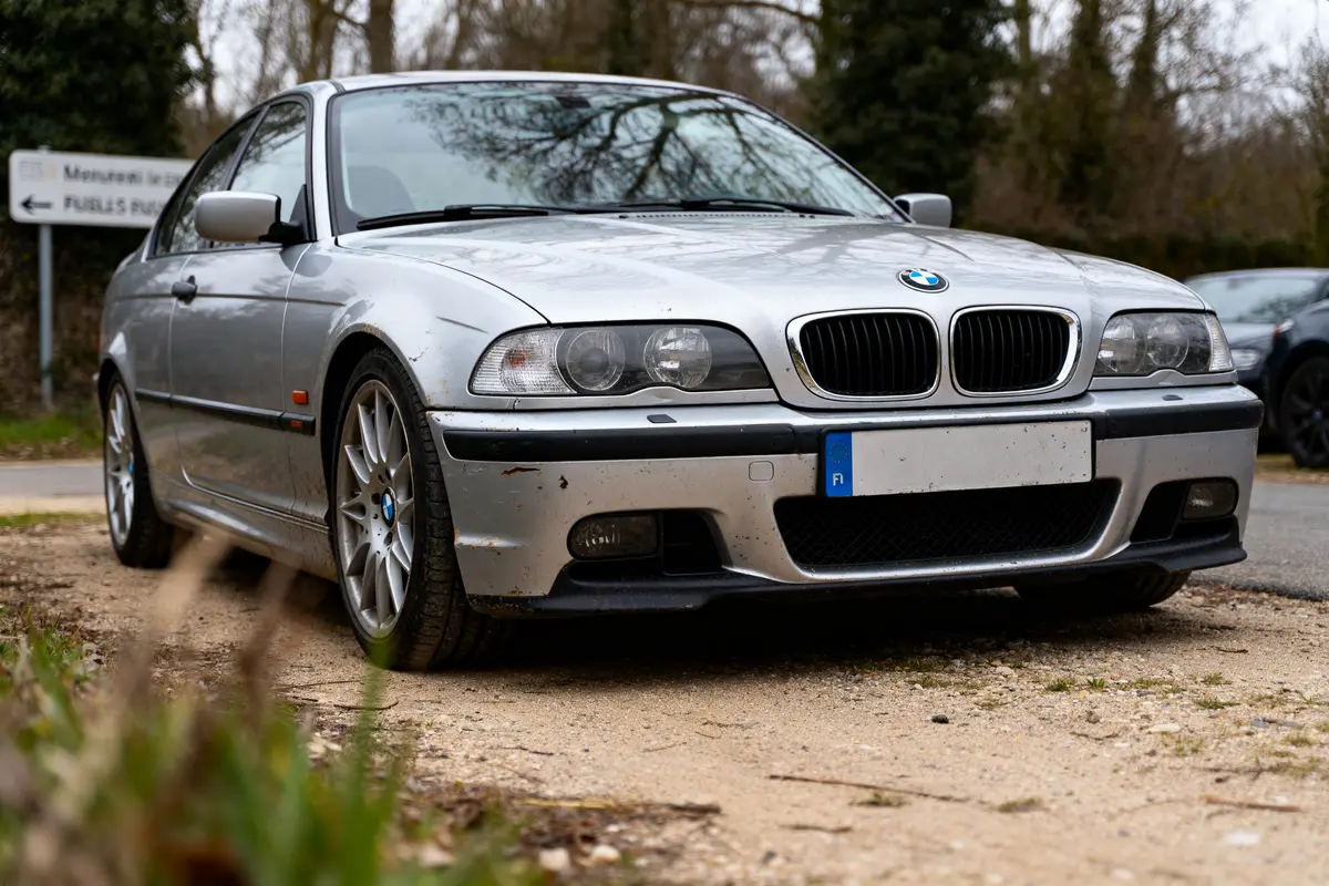 BMW E46 argenté stationné sur un chemin de terre en milieu rural