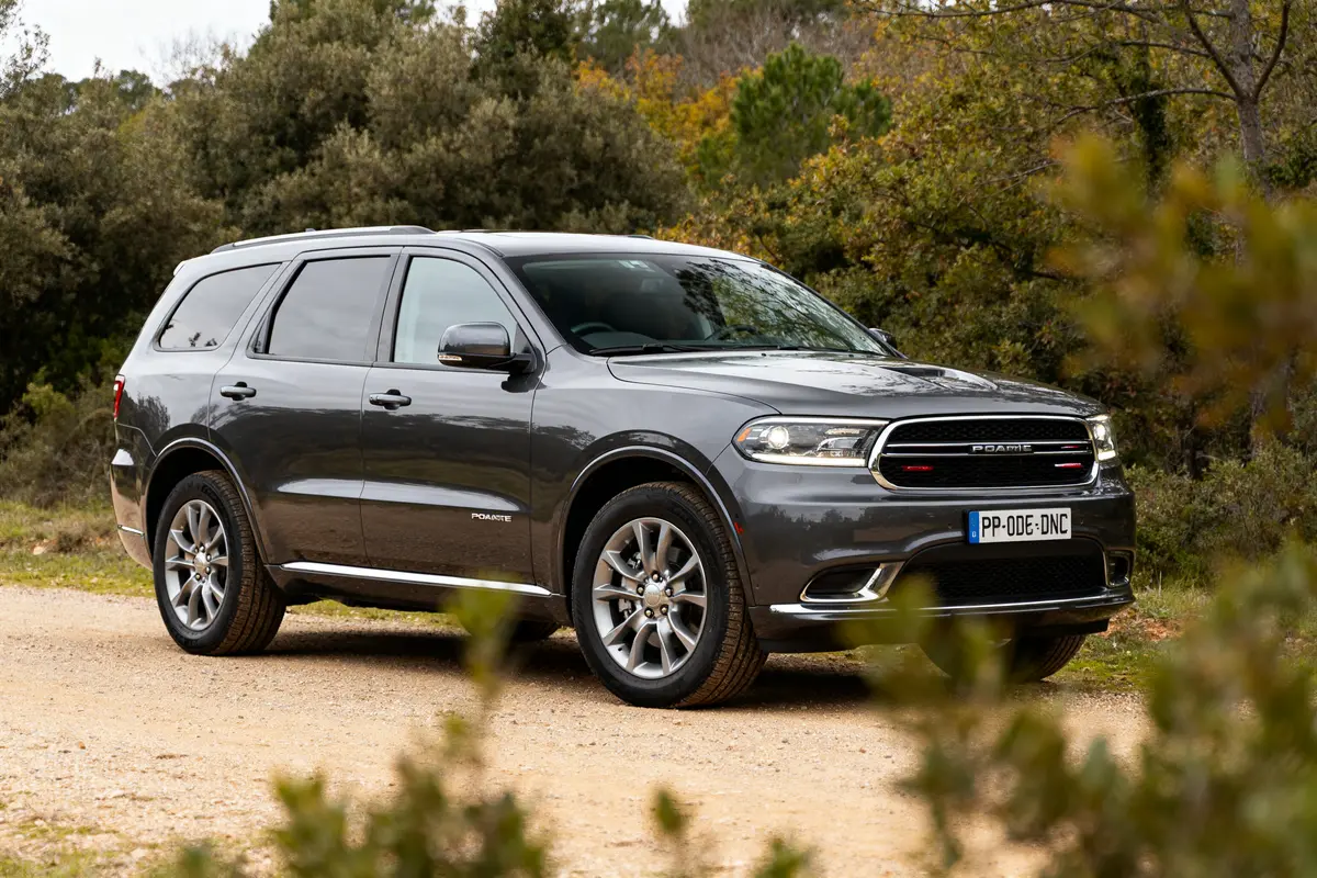 SUV gris Dodge Durango stationné sur chemin, entouré de végétation verdoyante