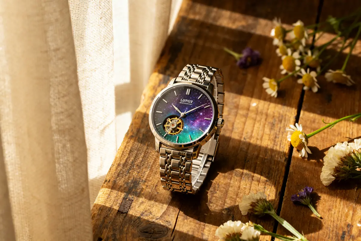 Montre Lotus automatique sur table en bois, cadran cosmique, fleurs autour, éclairage naturel