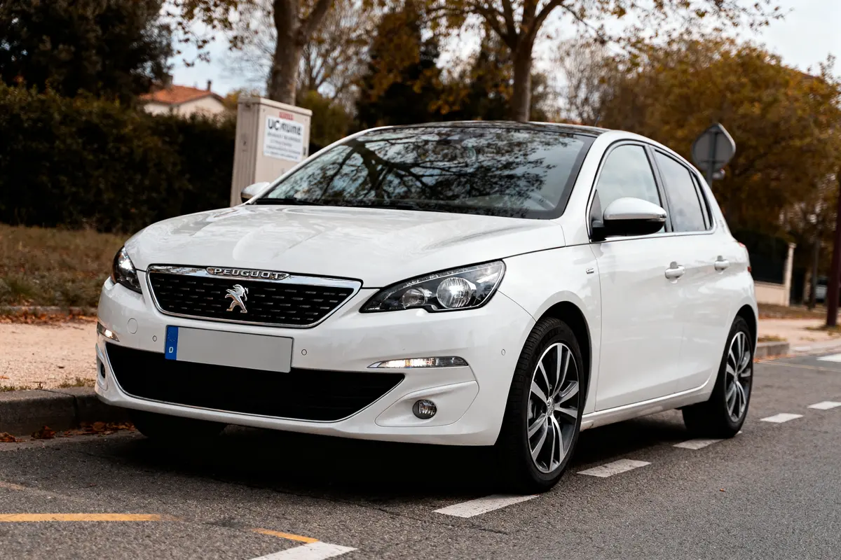 Voiture blanche stationnée sur la route, similaire à une Peugeot 201 moderne et stylée