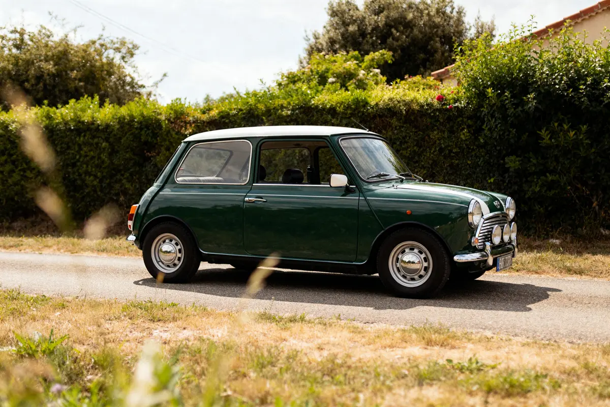 Voiture classique Austin Mini verte garée sur route entourée de verdure