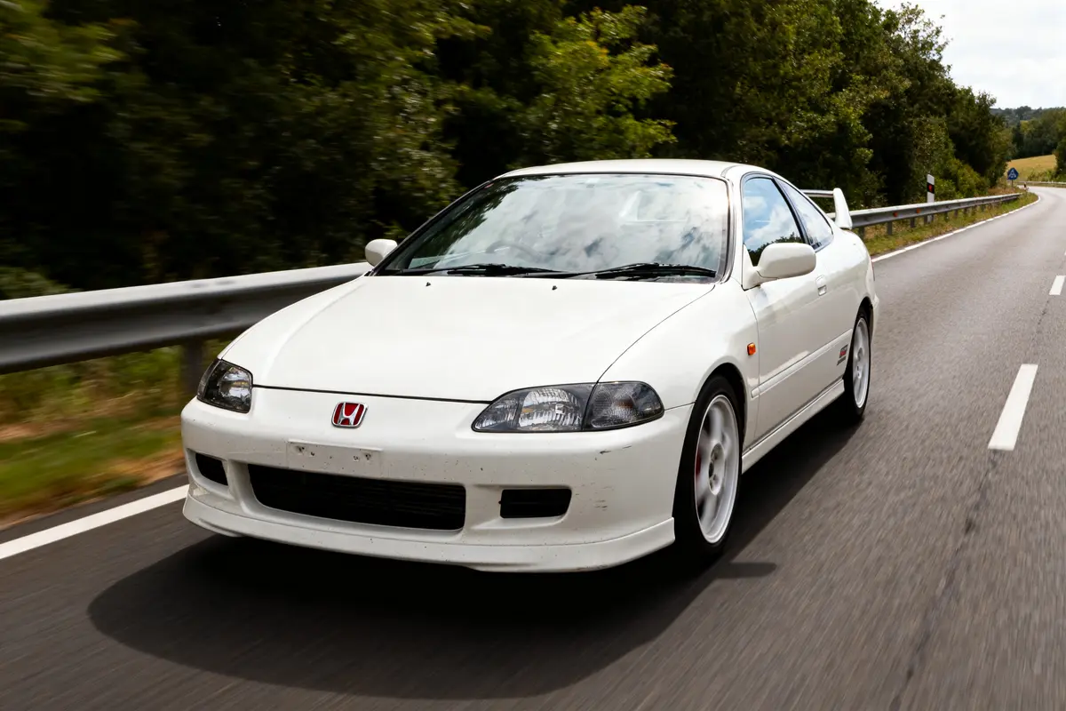 Voiture blanche sur route entourée d'arbres ctr Honda en mouvement rapide