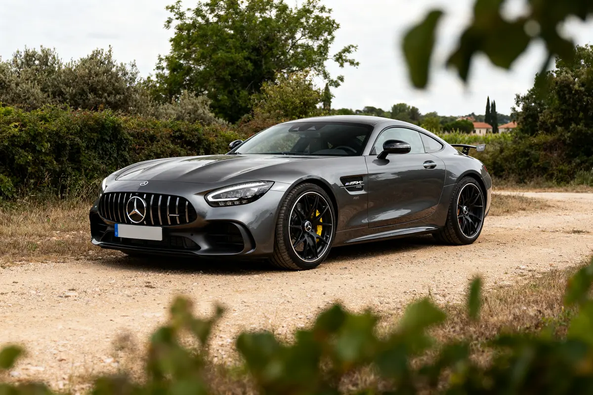 Voiture de sport grise mercedes-amg gran turismo sur chemin de campagne avec broussailles verdoyantes
