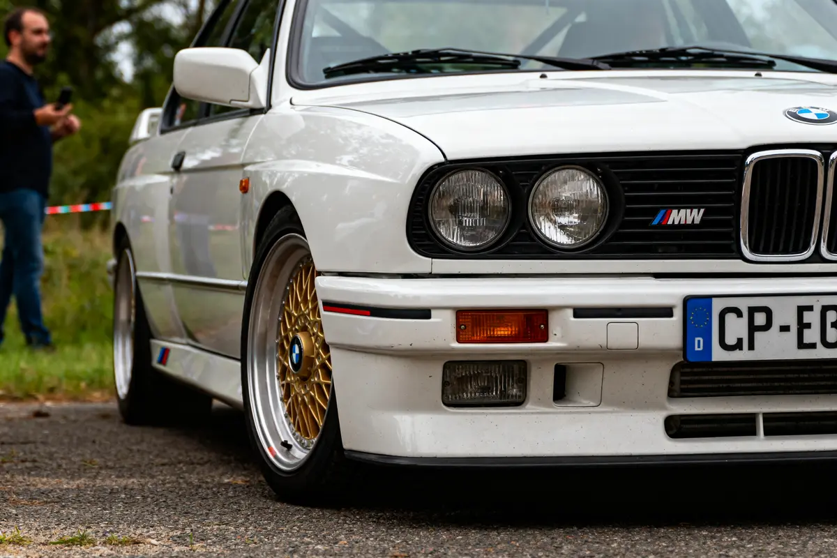 Vue avant d'une BMW M3 E30 blanche classique avec jantes dorées élégantes