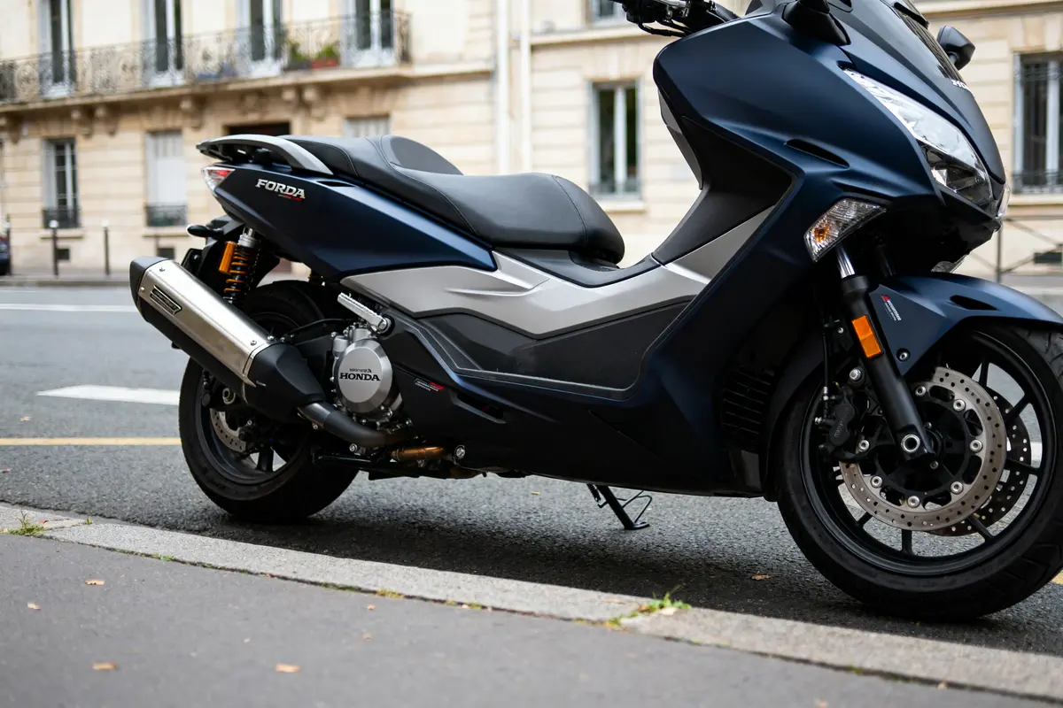 Scooter urbain Honda Forza 750 gris stationné sur le trottoir dans une rue parisienne