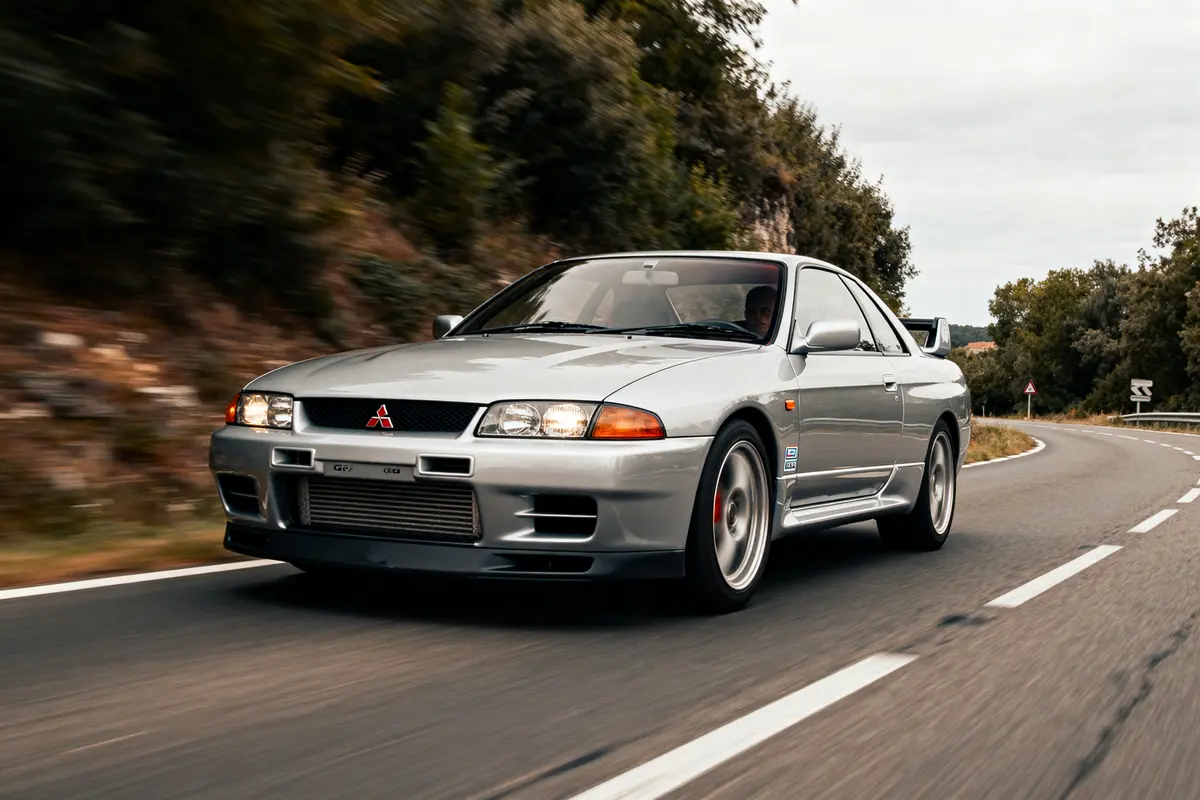 Voiture argentée sur une route sinueuse Mitsubishi GTR circulant rapidement en extérieur